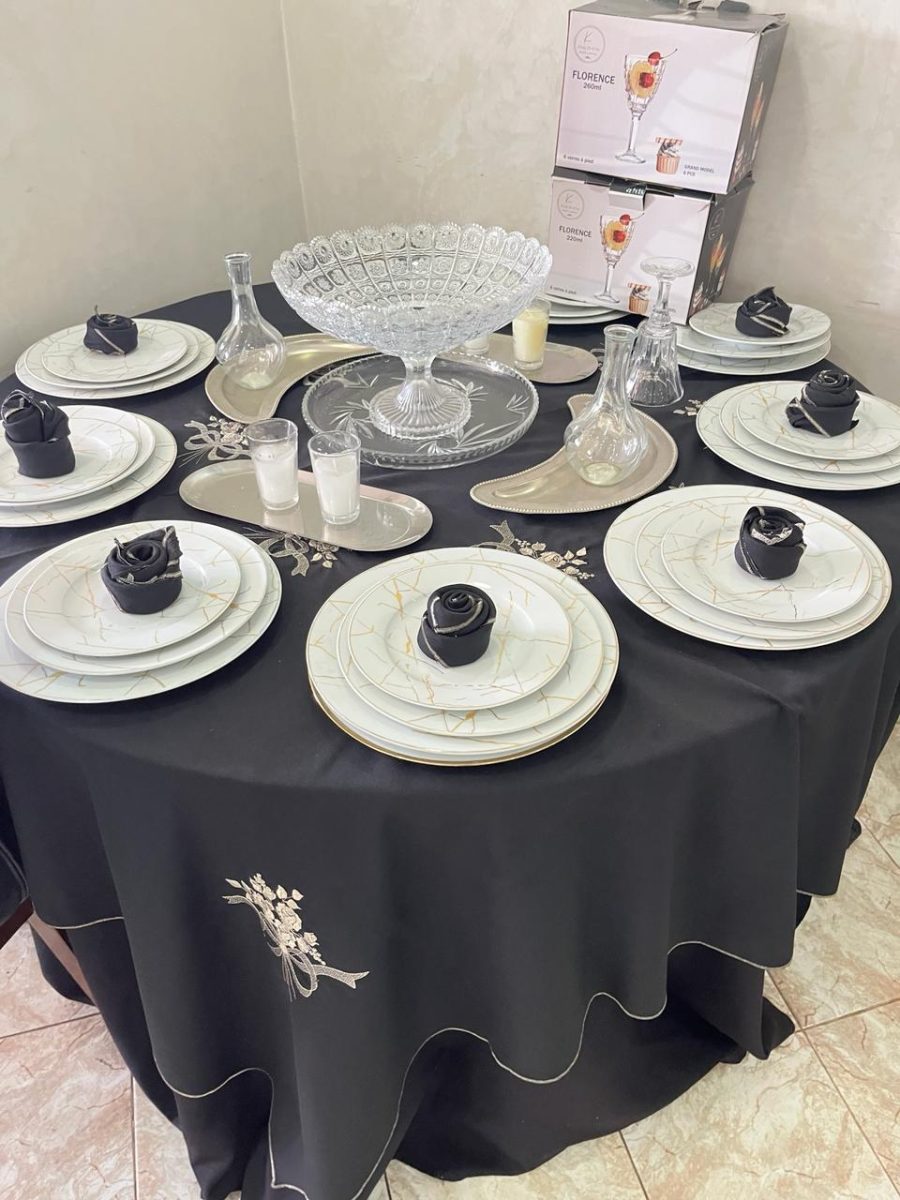 Table ronde en nappe noire avec vaisselle marbrée et serviettes en rose noire