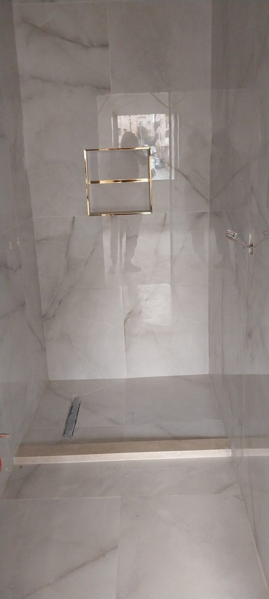 Douche habillée de carrelage effet marbre gris avec niche et caniveau