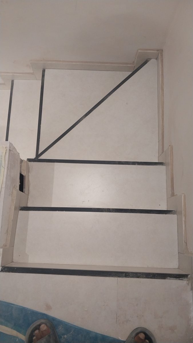 Escalier carrelé clair à nez de marches noirs