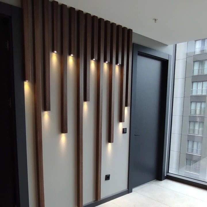 Habillage mural en tasseaux verticaux à spots LED près d'une porte
