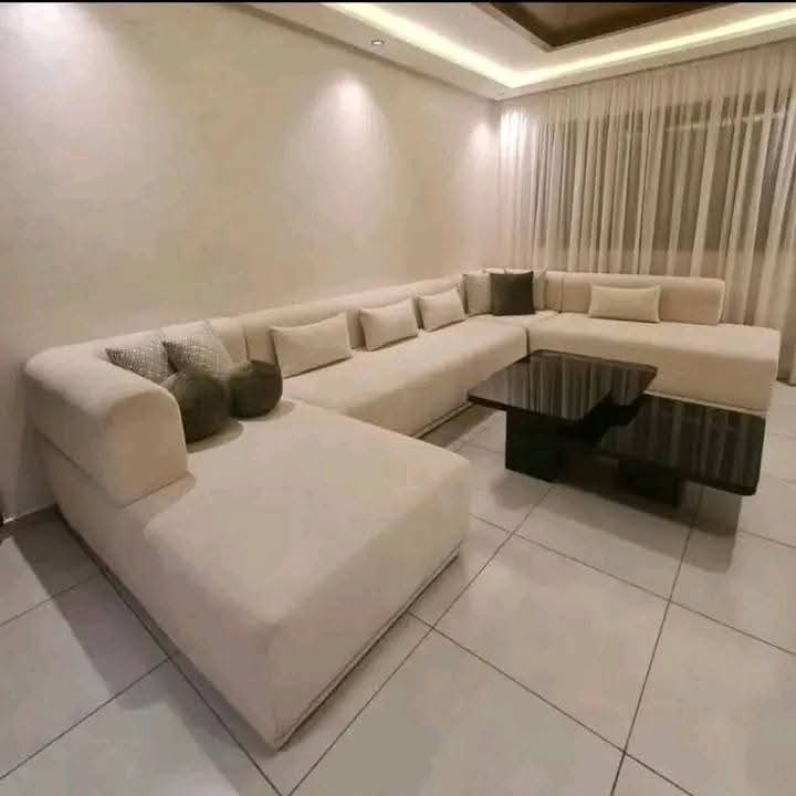 Grand salon d'angle en U tapissé beige avec table basse laquée