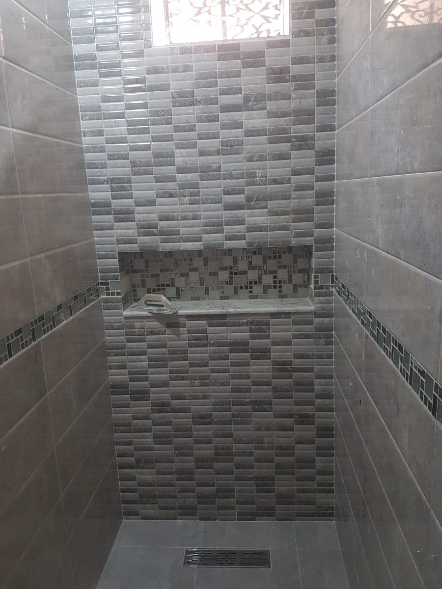 Douche habillée de faïence grise et frise mosaïque avec niche