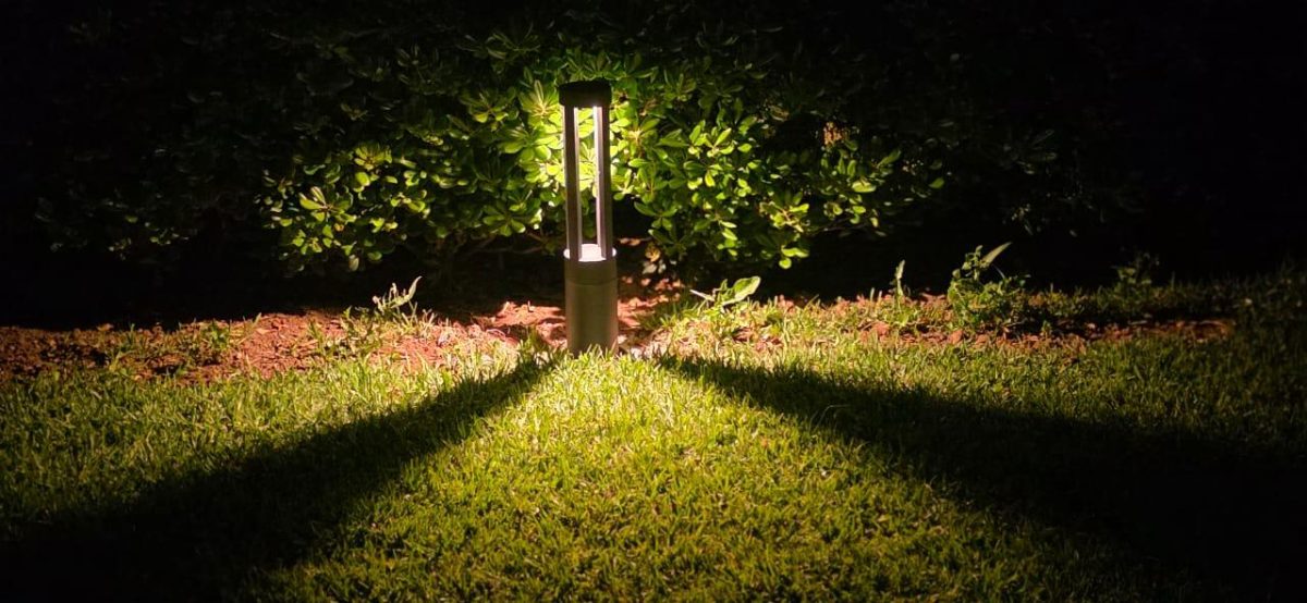 Borne d'éclairage extérieur allumée dans un jardin la nuit