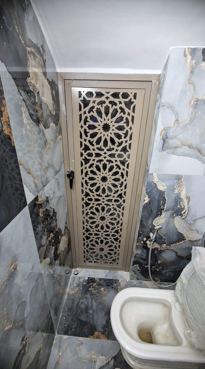 Porte en aluminium à découpe laser arabesque dans une salle d'eau en marbre