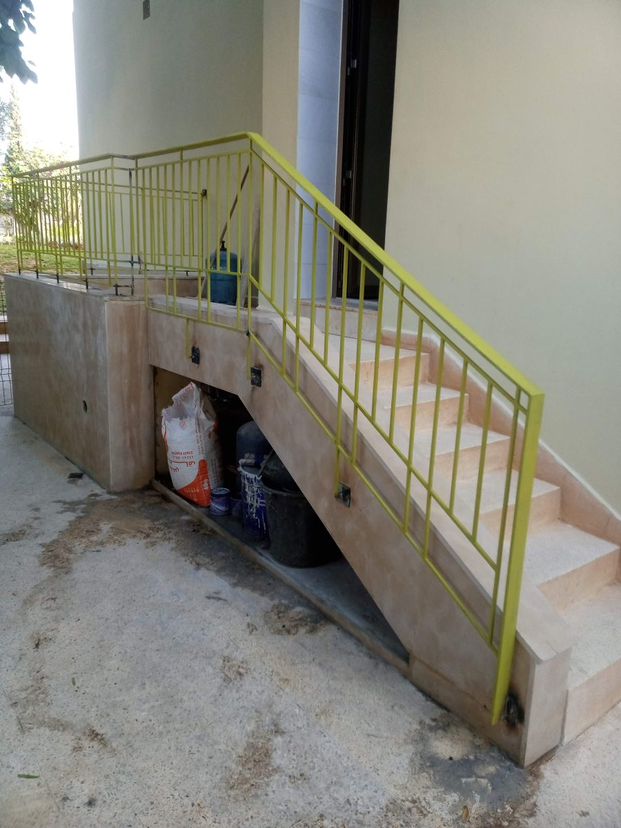 Escalier extérieur en pierre à garde-corps métallique jaune