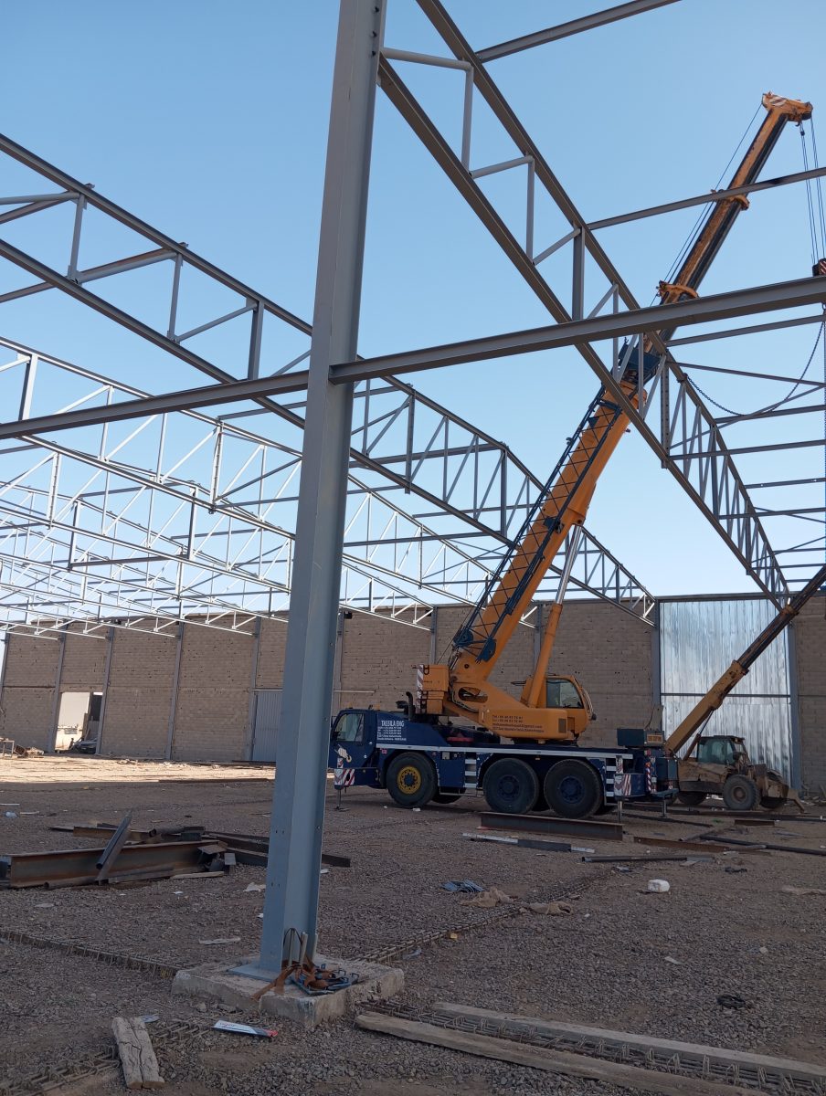 Charpente métallique de hangar en cours d'érection avec grue mobile