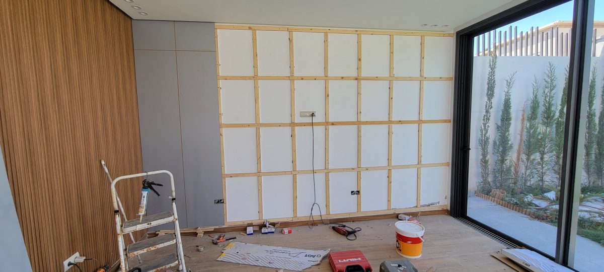 Habillage mural en bois et ossature en cours de pose dans un séjour