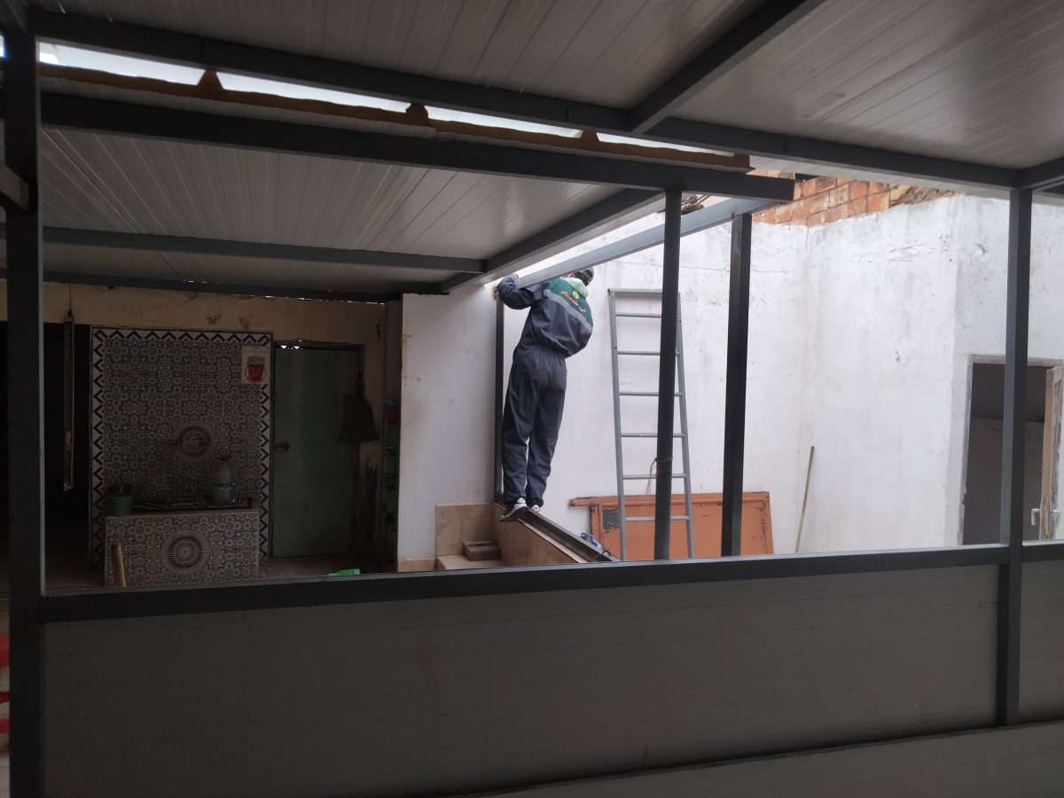 Pose d'une véranda en aluminium et acier au-dessus d'un patio