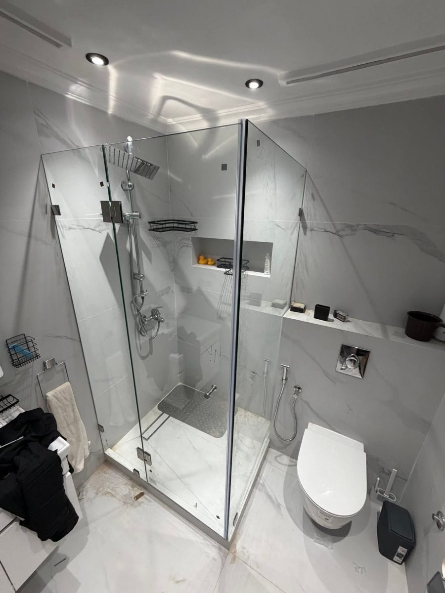 Cabine de douche d'angle en verre dans une salle de bain en marbre