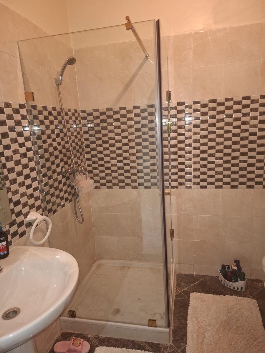Paroi de douche en verre dans une salle de bain carrelée effet marbre et mosaïque
