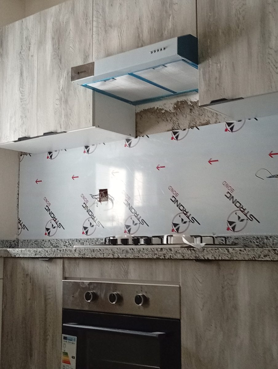 Cuisine effet bois gris avec plan en granit et hotte, en cours de pose