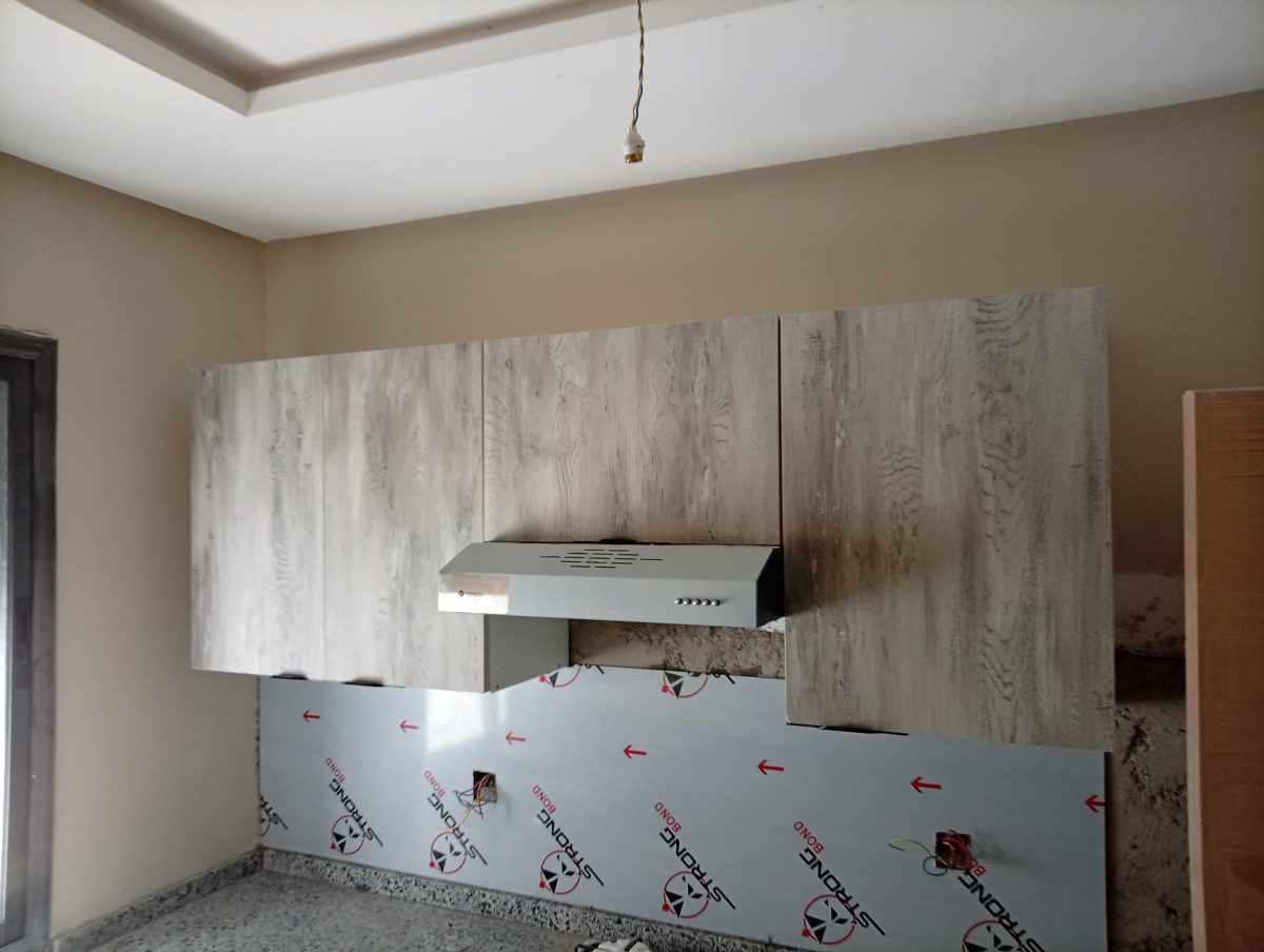 Meubles hauts de cuisine effet bois gris avec hotte, en cours de pose