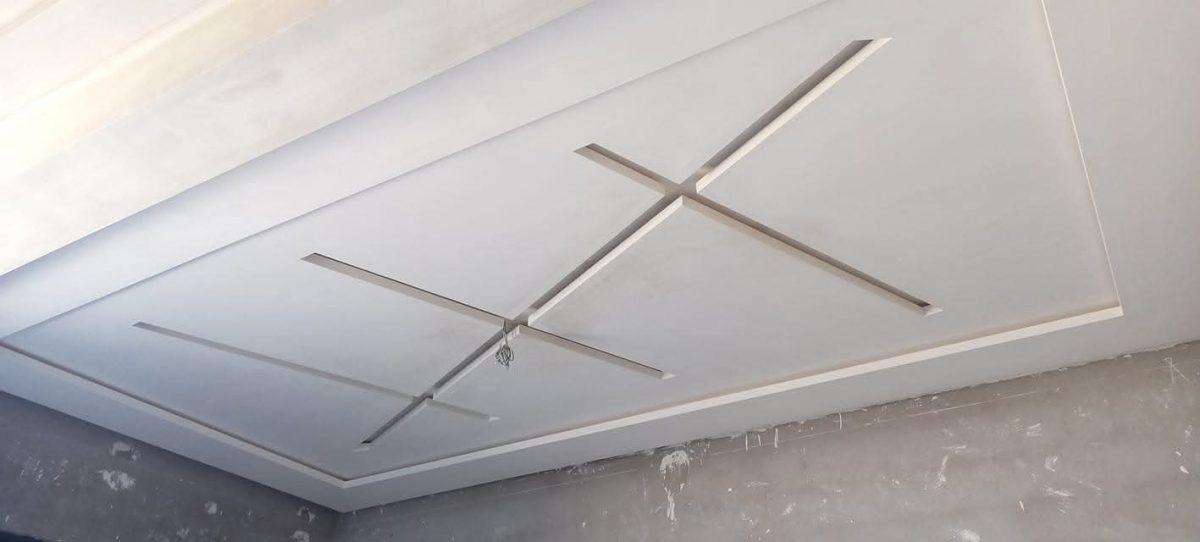 Faux plafond gris à décrochés et motif en croix, en cours