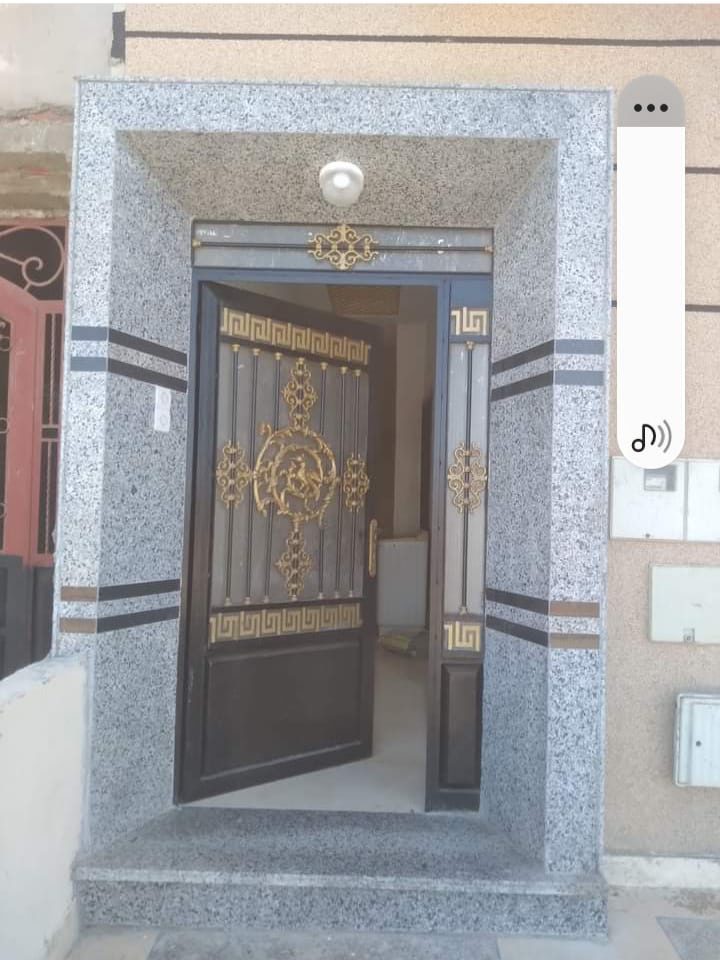 Encadrement d'entrée en granit gris avec porte en fer forgé décorée