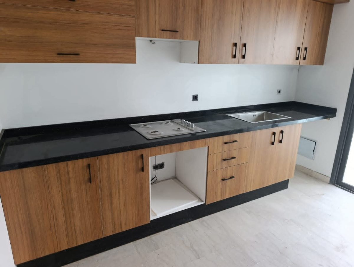 Cuisine équipée en bois avec plan en granit noir et plaque de cuisson