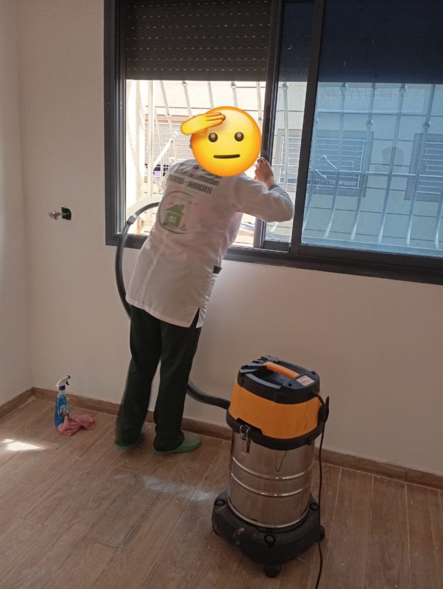 Agent de nettoyage aspirant et nettoyant près d'une fenêtre