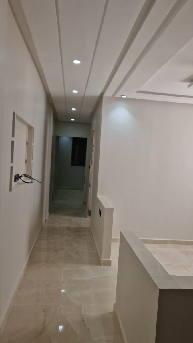 Couloir peint en blanc avec faux plafond à spots