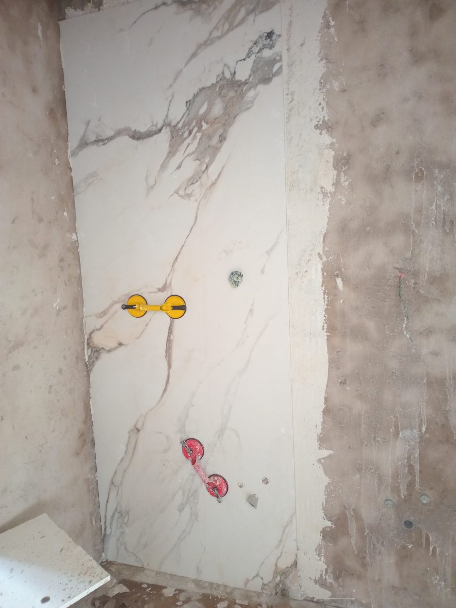 Pose d'un grand carreau effet marbre au mur à l'aide de ventouses