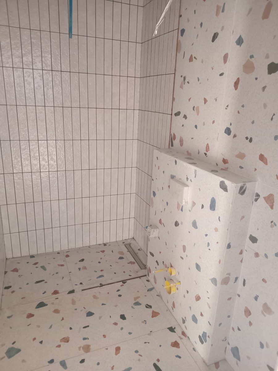 Salle d'eau en faïence blanche verticale et terrazzo, en cours