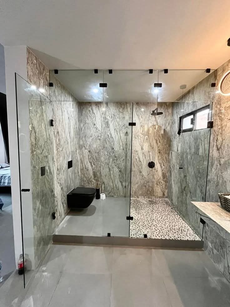 Cabine de douche en verre dans une salle de bain en marbre