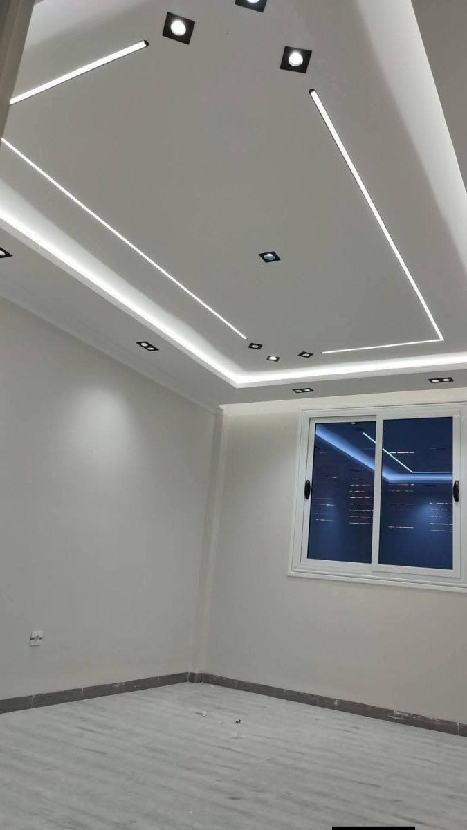Faux plafond design à lignes lumineuses LED et spots dans une pièce