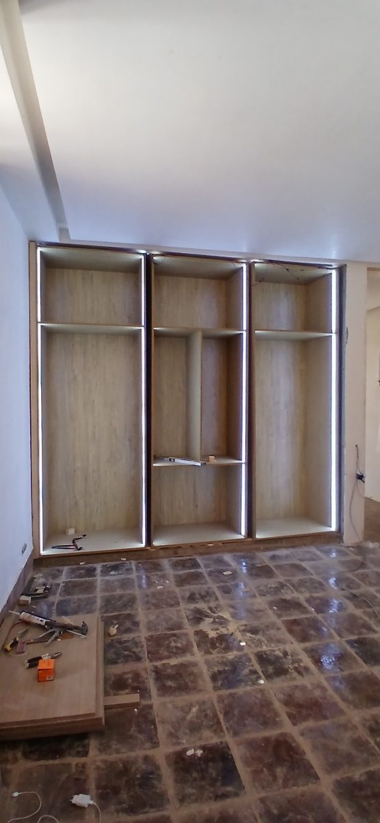 Meuble mural en bois à niches avec éclairage LED, en cours de pose