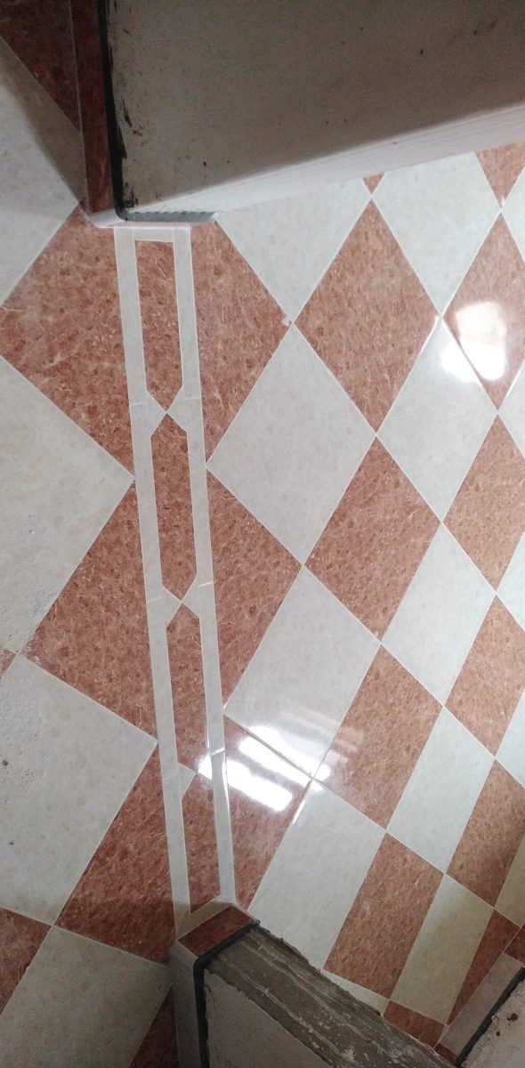 Sol carrelé à motif losange rouge et beige avec insert décoratif