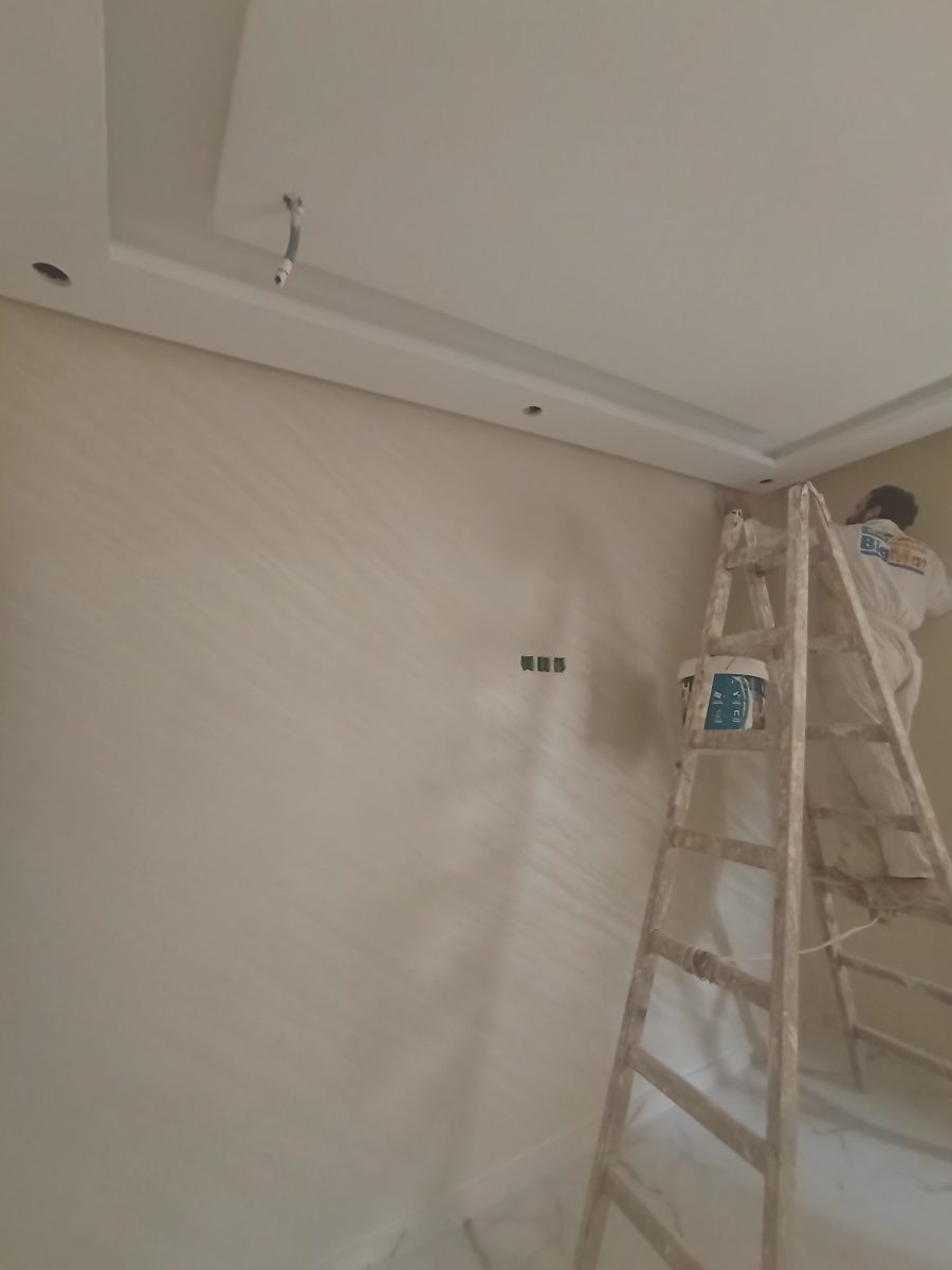 Pièce en cours de peinture à mur beige et faux plafond