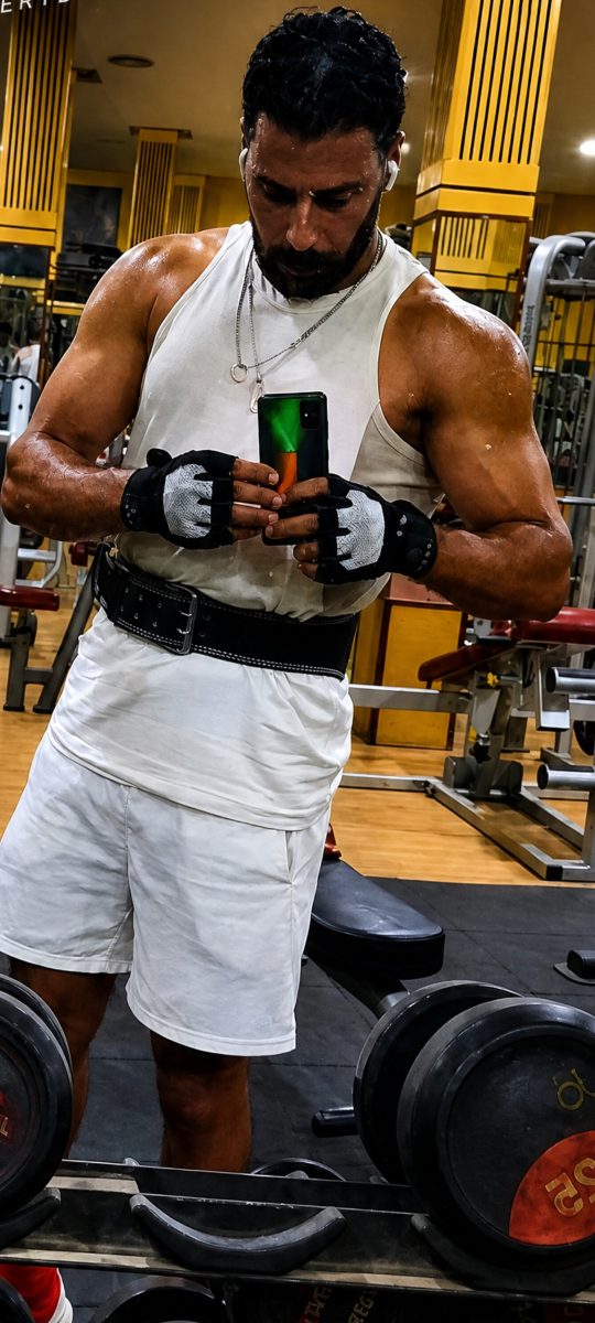 Coach sportif équipé (ceinture et gants) en salle de musculation