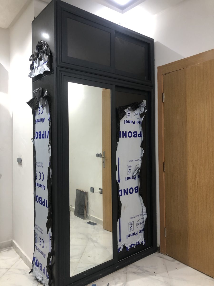 Cloison en aluminium noir avec porte et miroir en cours d'installation