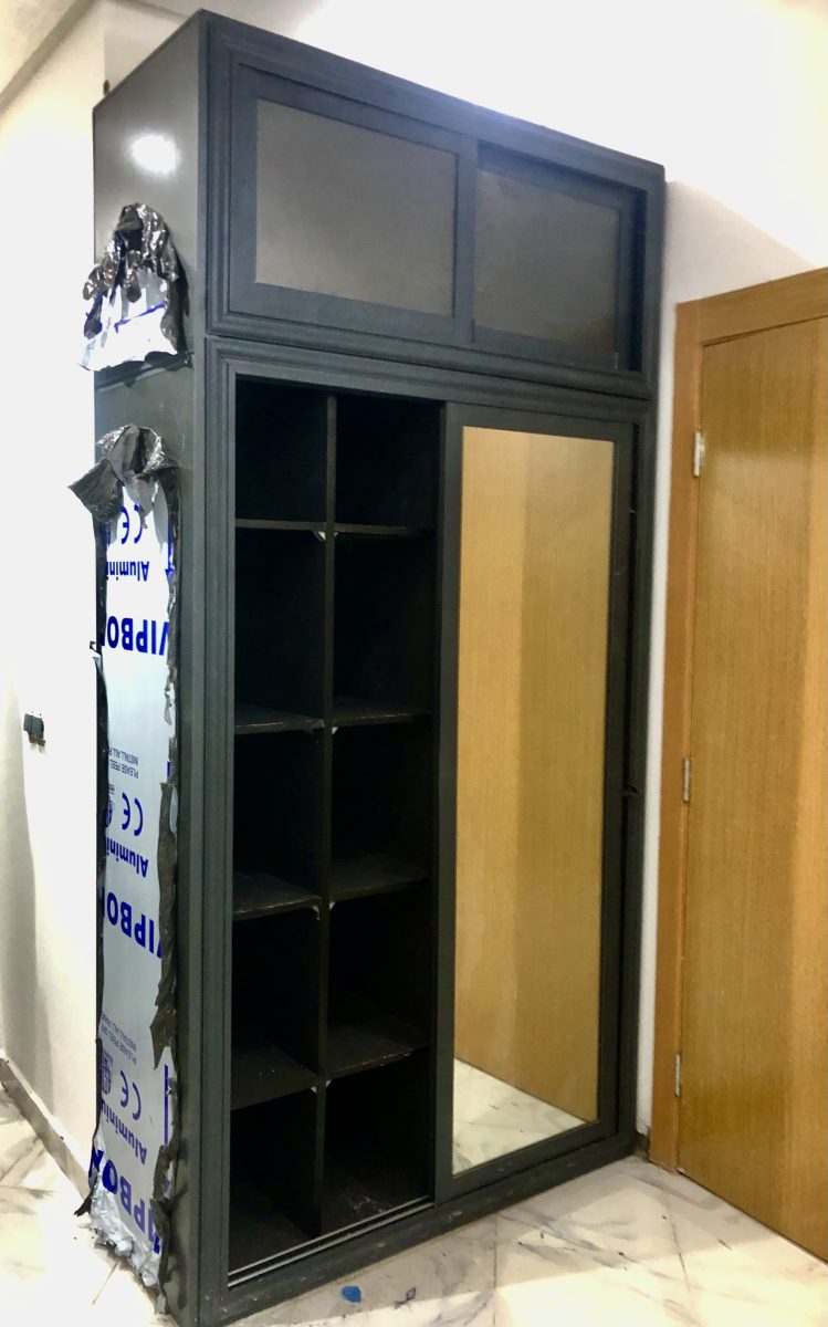 Dressing en aluminium gris à étagères et porte coulissante, en cours de pose