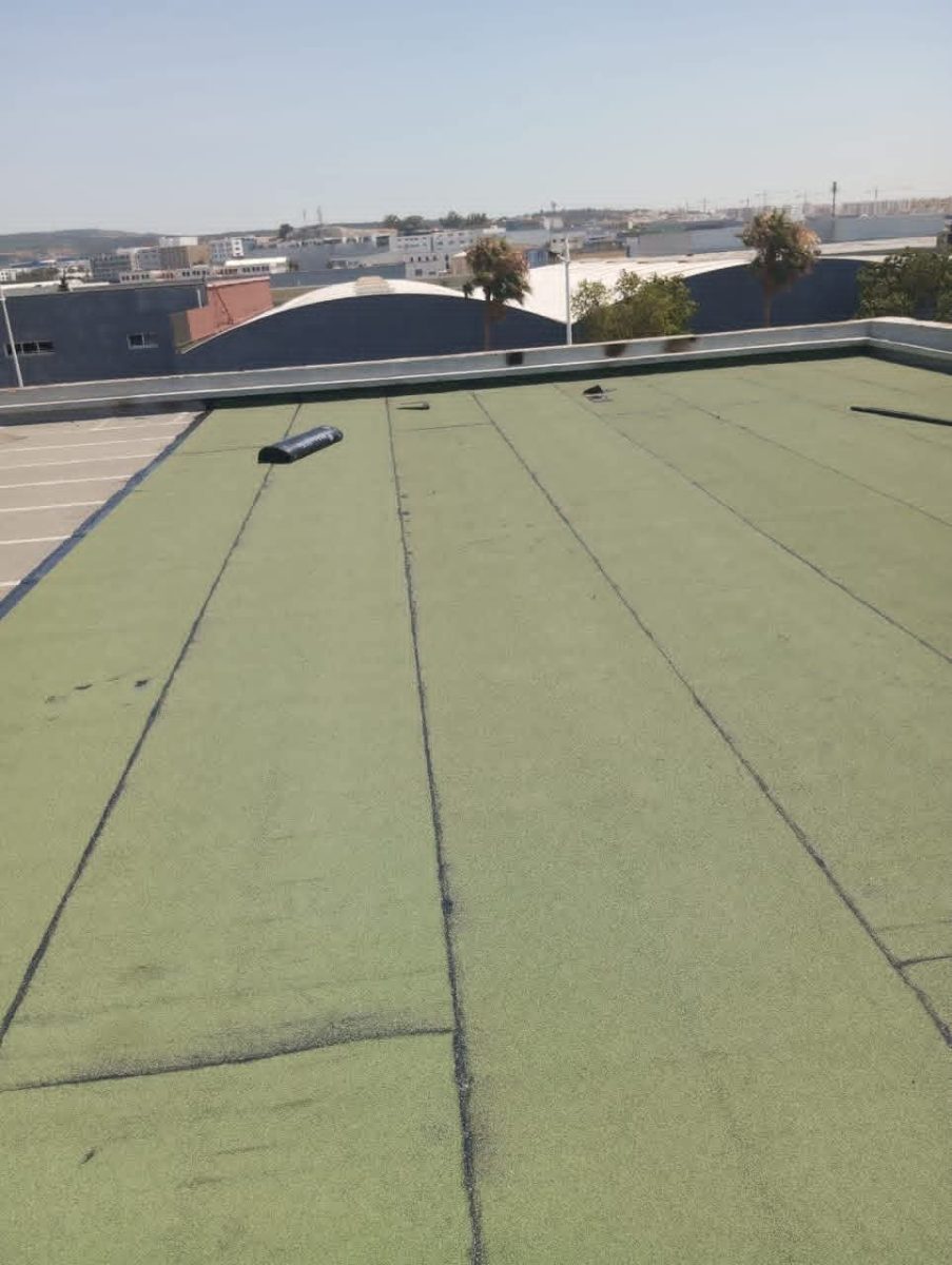 Toiture-terrasse étanchée avec membrane verte, vue sur zone urbaine