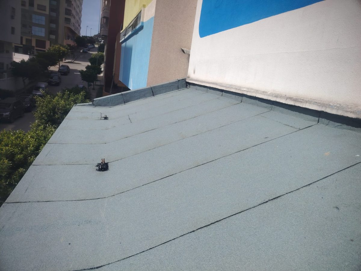 Toiture-terrasse étanchée avec membrane verte, vue sur rue