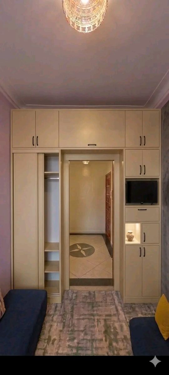 Rangements sur mesure beige encadrant un passage, avec niche TV