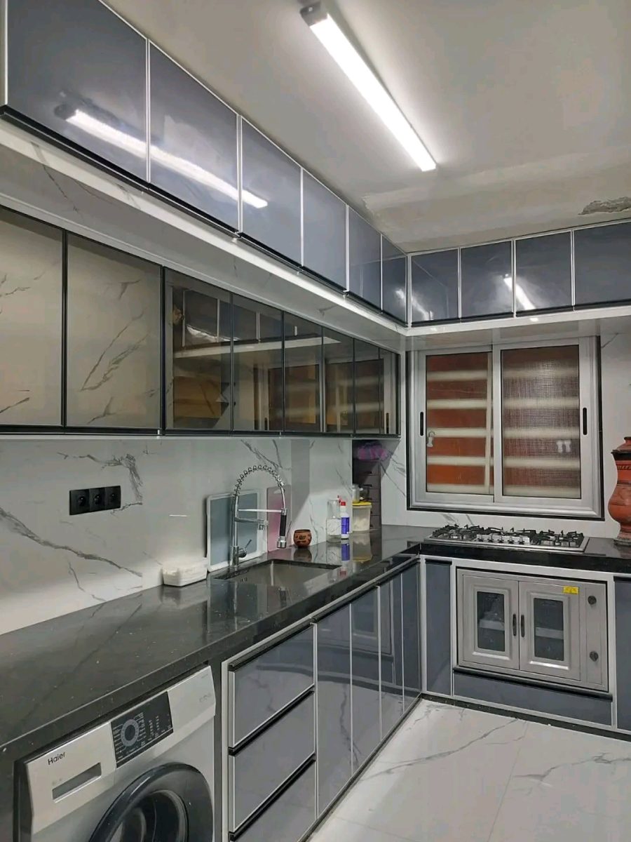 Cuisine en aluminium gris avec vitrines, plan foncé et fenêtre coulissante