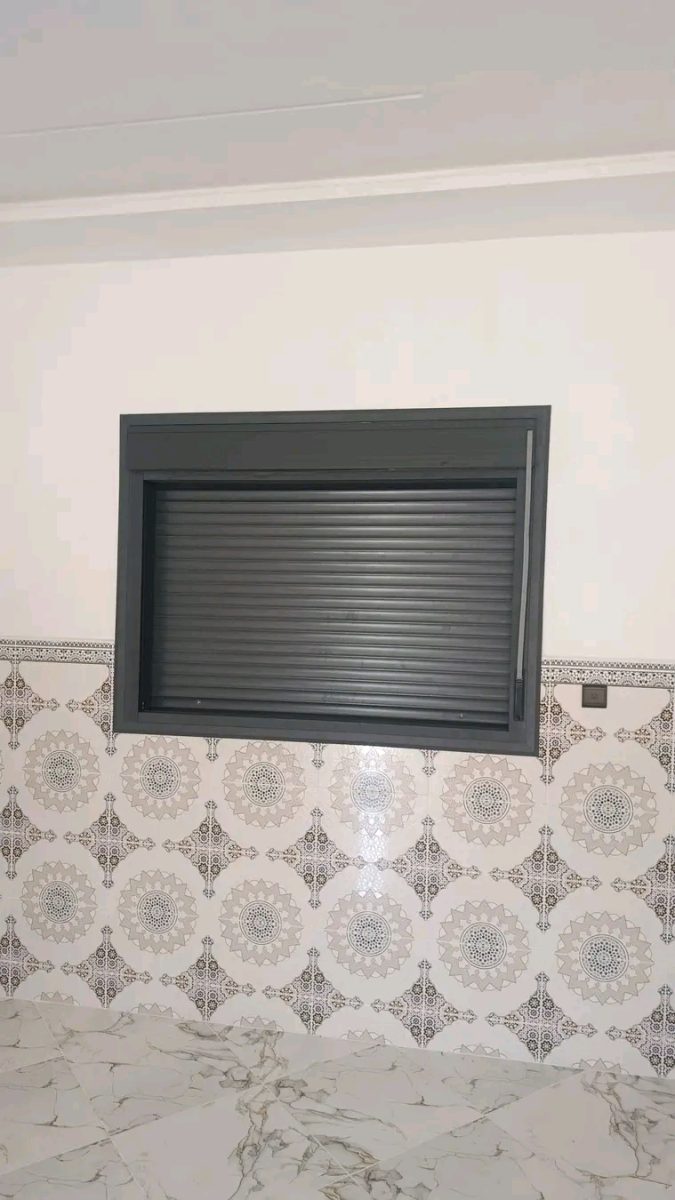 Fenêtre en aluminium anthracite à volet roulant sur faïence à motifs