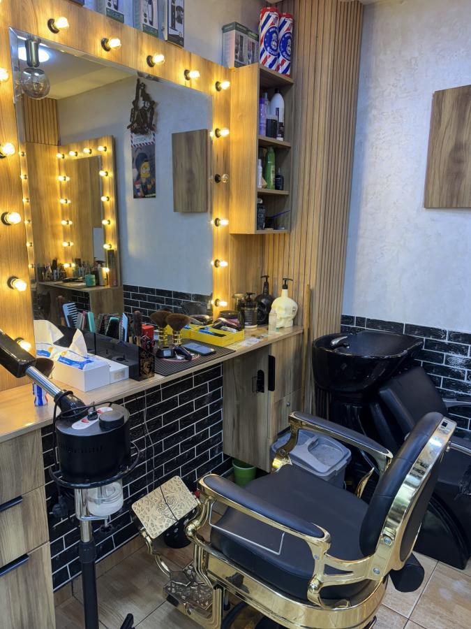 Coin coiffure avec miroir à ampoules, fauteuil doré et bac de lavage