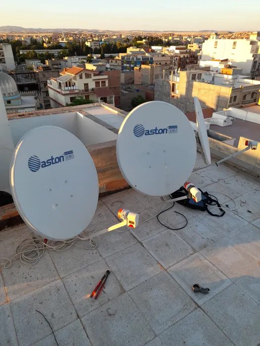 Deux antennes paraboliques installées sur une toiture avec vue sur la ville