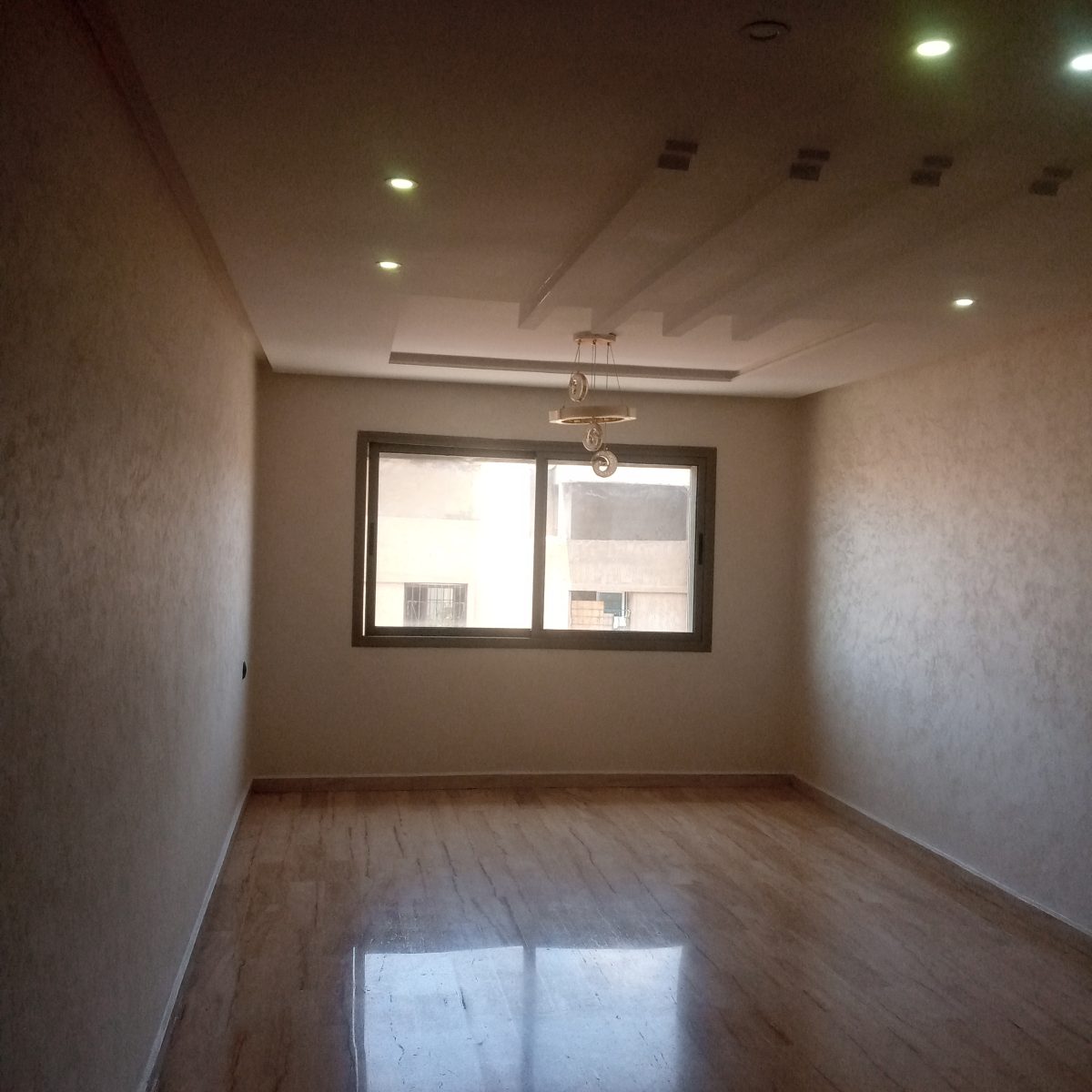 Séjour en enduit décoratif nacré beige avec faux plafond et sol travertin