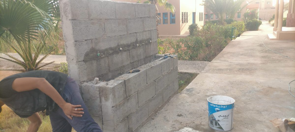 Lavabo collectif extérieur en cours de maçonnerie avec robinets