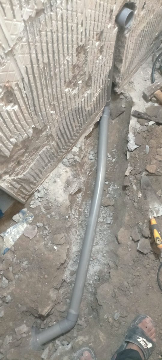 Pose d'une évacuation en PVC gris dans une saignée au sol
