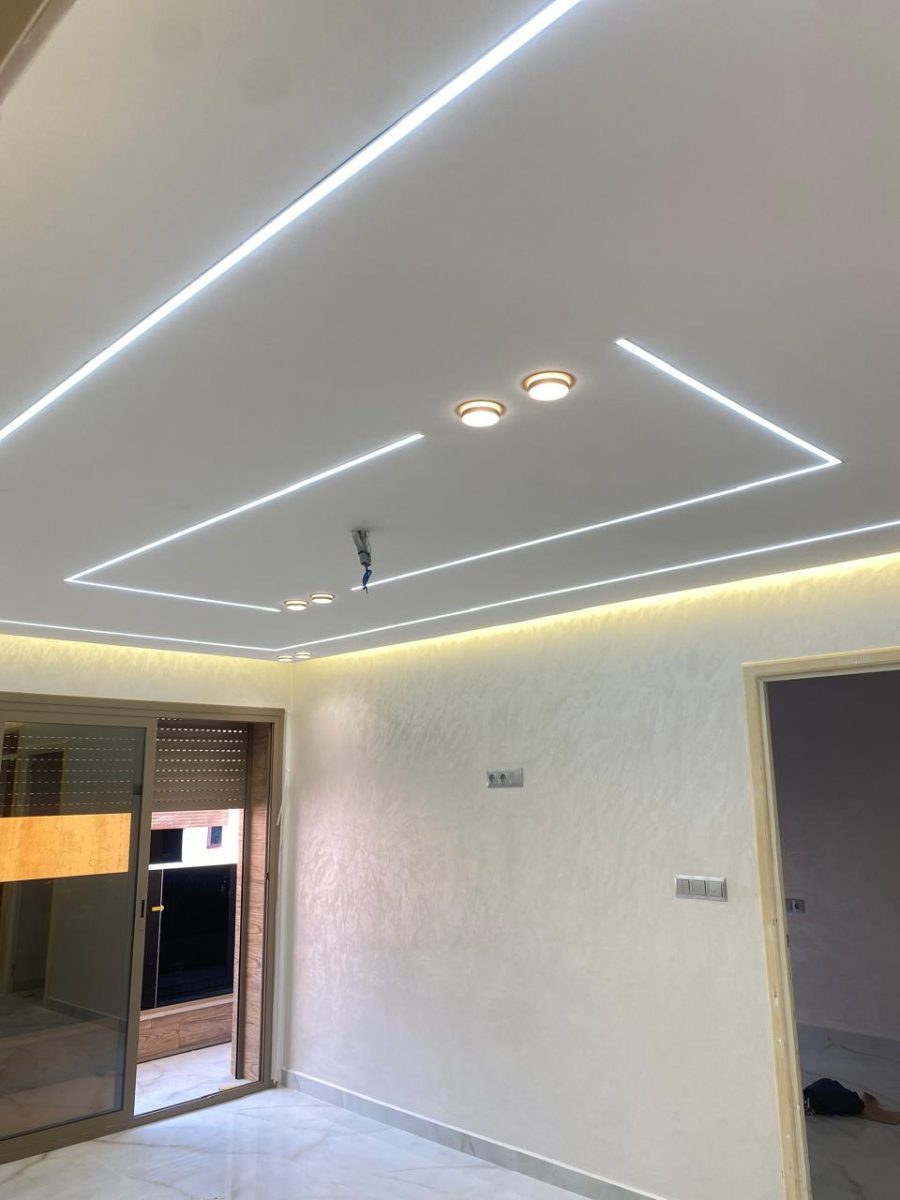 Faux plafond à lignes LED en chevron et murs en peinture nacrée