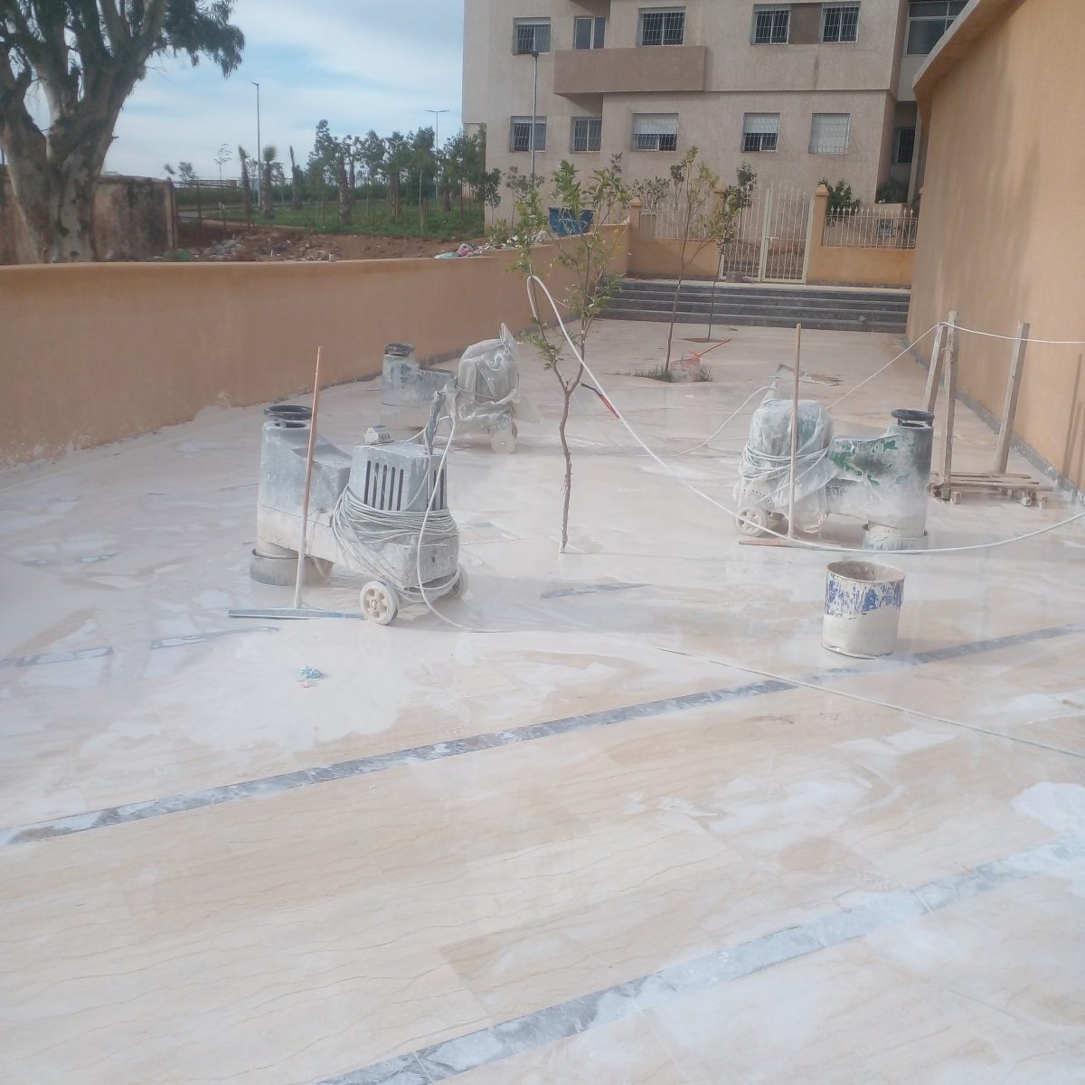 Ponçage d'un grand sol en marbre beige extérieur à la surfaceuse