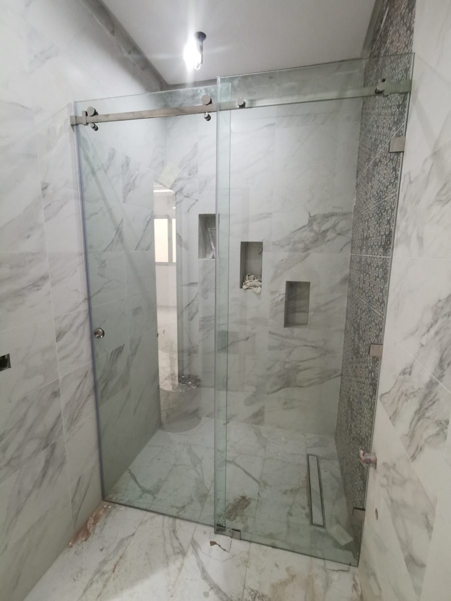 Cabine de douche en verre coulissant dans une salle de bain en marbre
