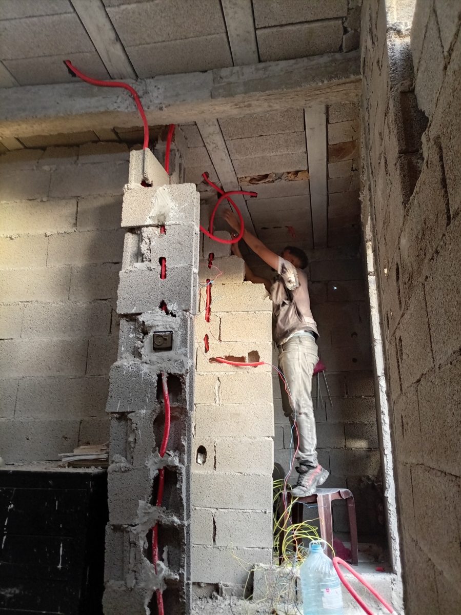 Passage de gaines électriques rouges dans un mur, en cours