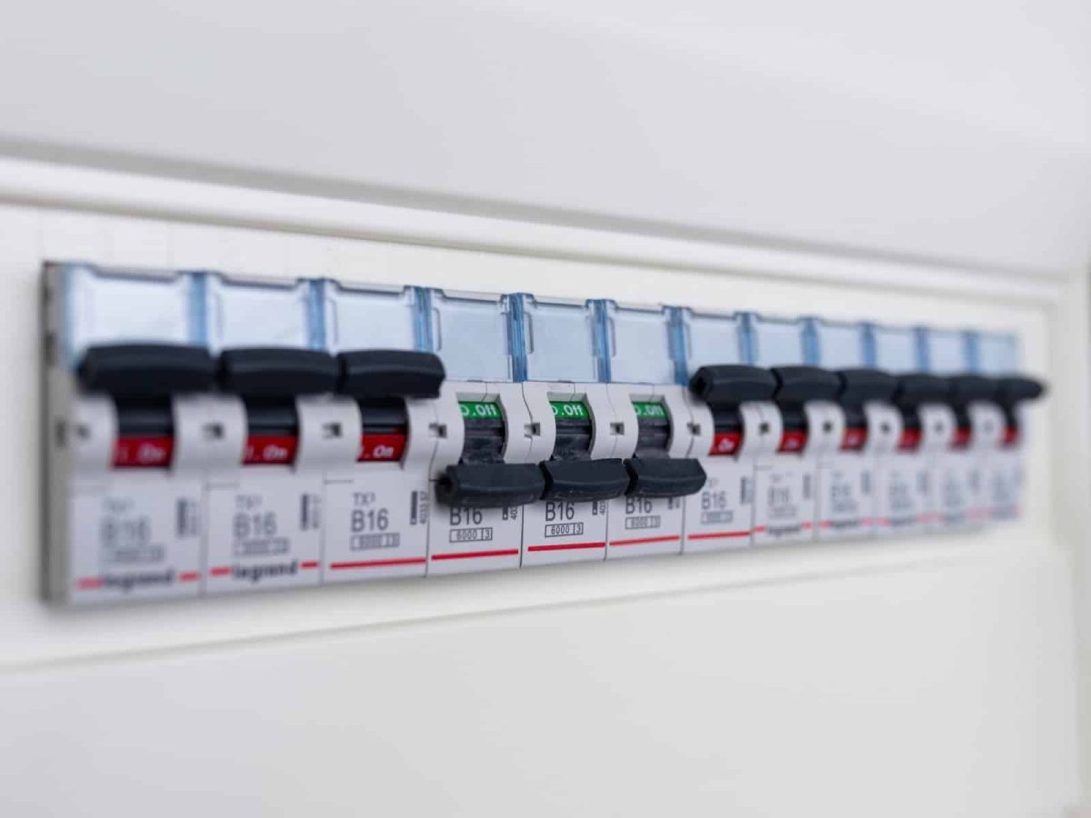 Rangée de disjoncteurs sur un tableau électrique blanc