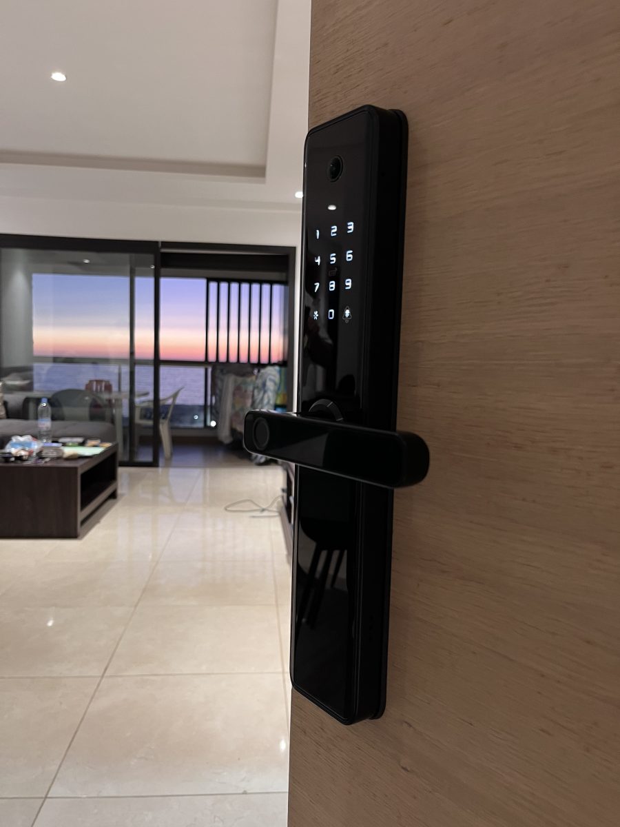Serrure connectée à clavier sur une porte, vue mer en arrière-plan