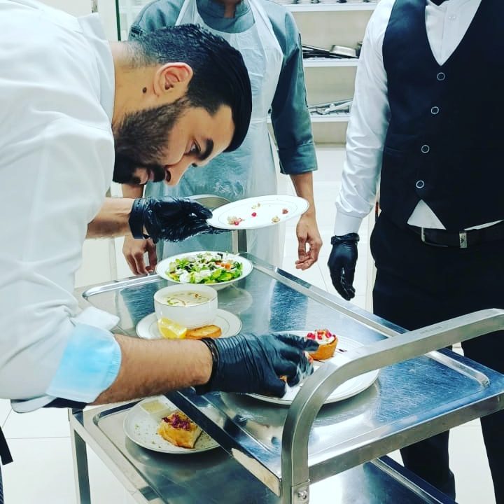 Cuisinier dressant des assiettes sur un chariot en cuisine pro