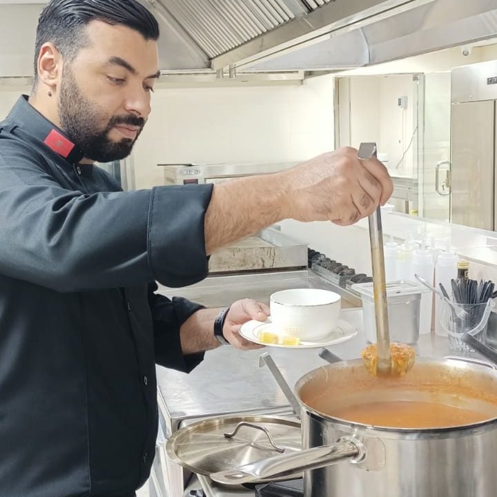 Cuisinier servant une soupe à la louche en cuisine professionnelle