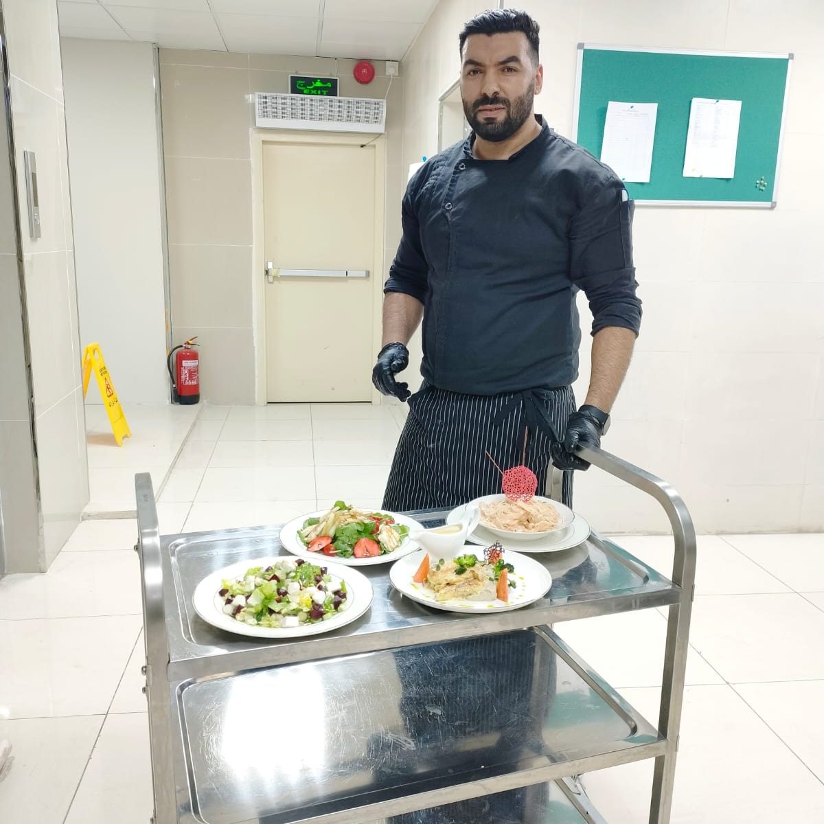 Cuisinier présentant des assiettes dressées sur un chariot
